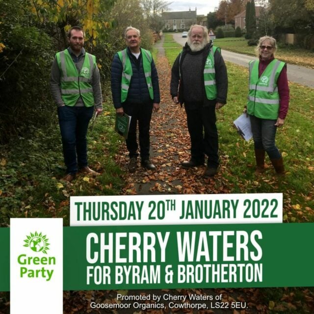 Four people with green waistcoats stood on a leafy footpath