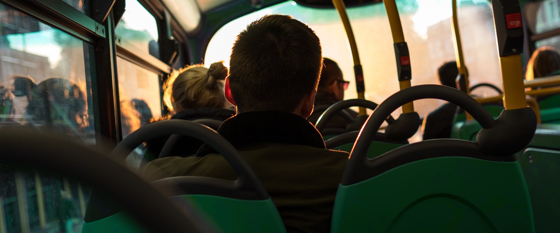 Passengers sat on a bus with green seats at sunset