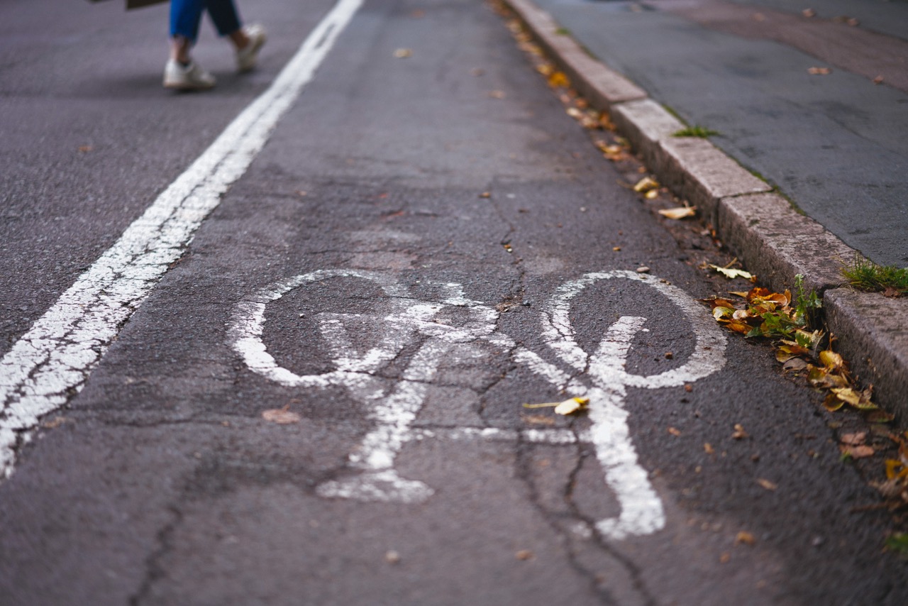 Cycle lane next to a raised footpath. Cracked tarmac.