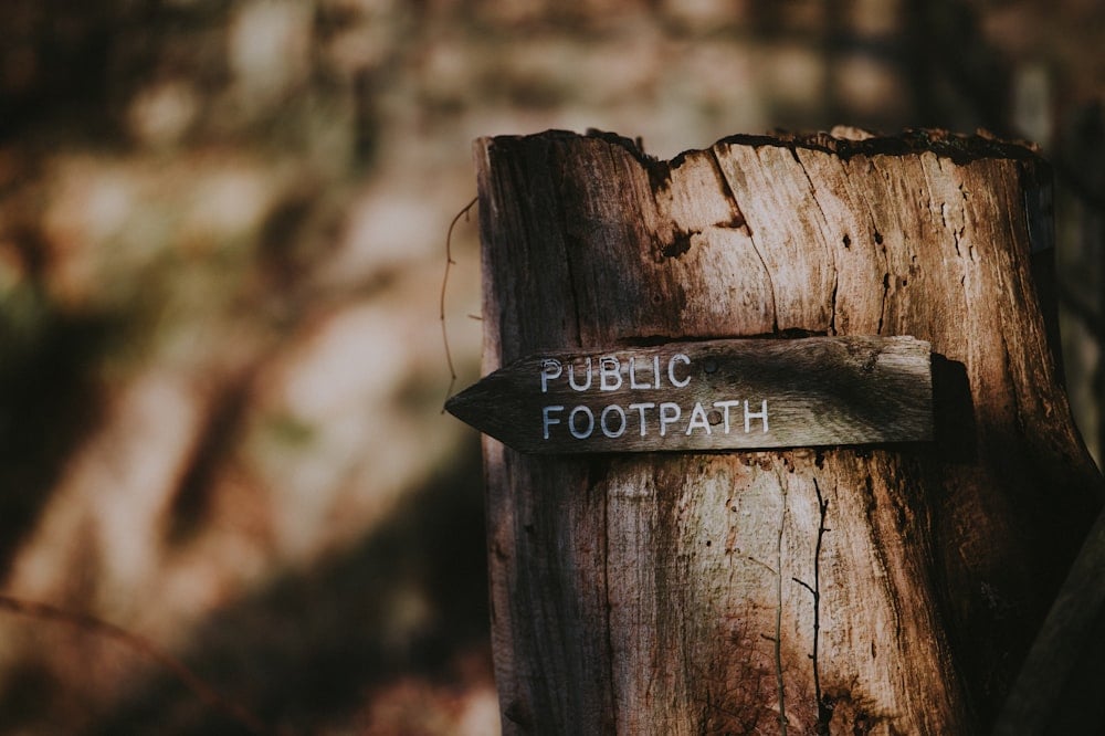 Wooden public footpath sign on a tree stump